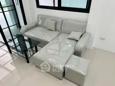 Modern living room with sleek gray sofa and glass coffee table in a bright space.