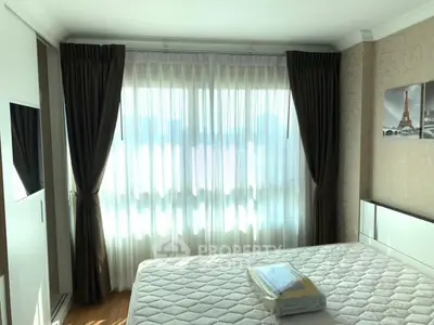 Bright bedroom with large window and elegant curtains, featuring a comfortable bed and stylish decor.