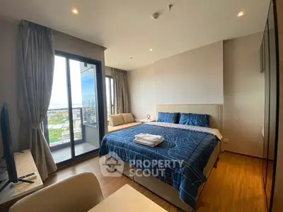Spacious bedroom with large window and balcony offering stunning city views.