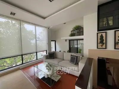 Elegant living room with large windows and modern decor, featuring a cozy sofa and stylish coffee table.