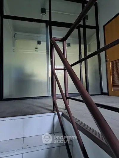Modern office entrance with sleek glass doors and metal railing