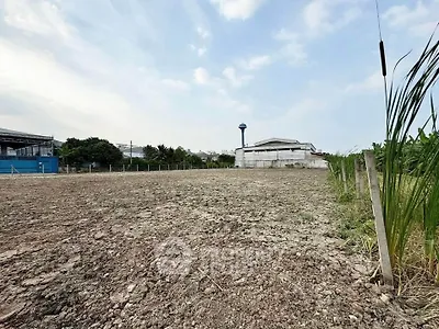 Expansive vacant land with potential for development, featuring clear skies and surrounding greenery.