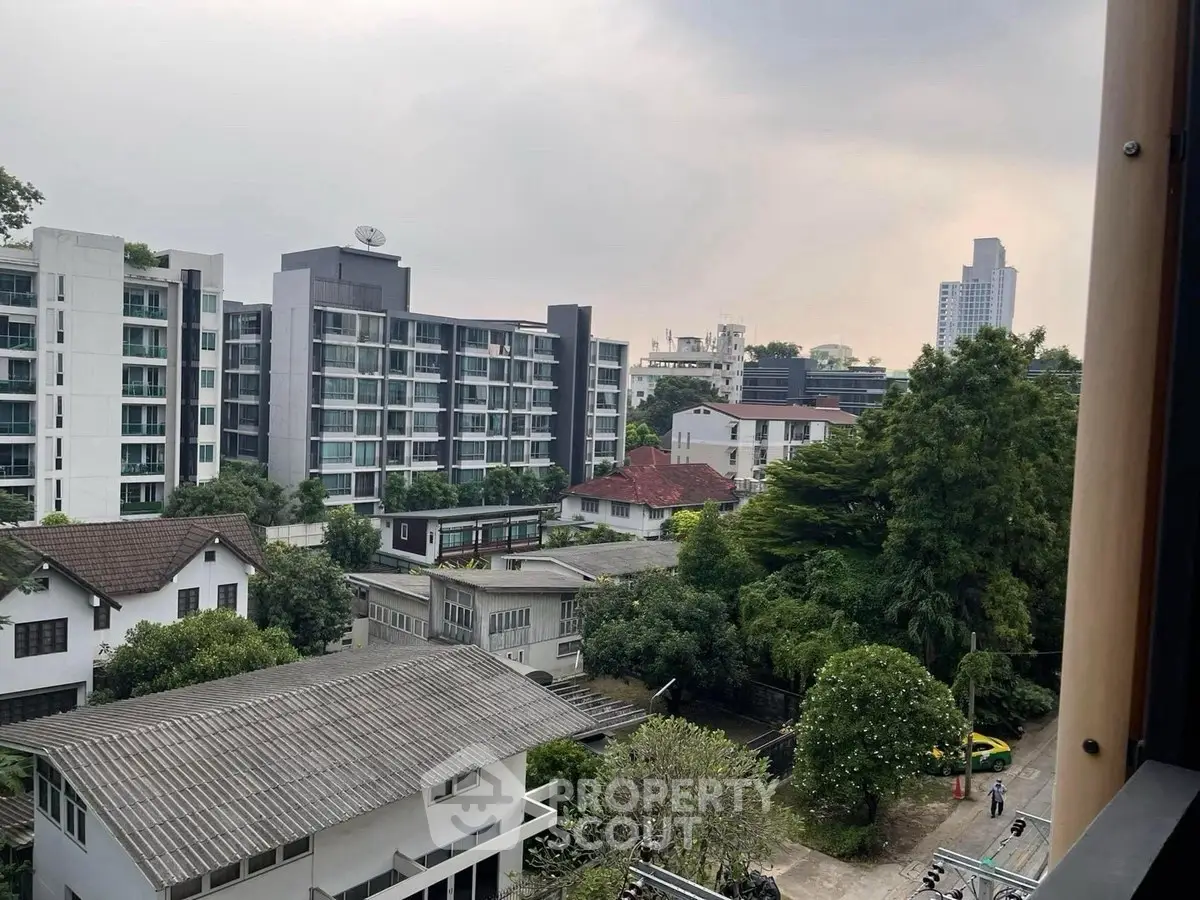Stunning urban view from a high-rise apartment showcasing modern buildings and lush greenery.