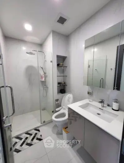 Modern bathroom with glass shower, sleek vanity, and elegant tile design.