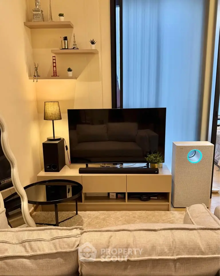 Cozy living room with modern decor, featuring a flat-screen TV, stylish shelves, and a comfortable sofa.
