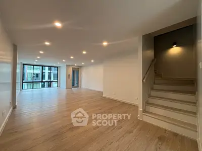 Spacious modern living room with wooden flooring and ample natural light