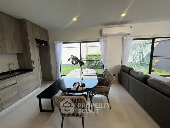 Modern open-plan living room with sleek kitchen and garden view, perfect for entertaining.