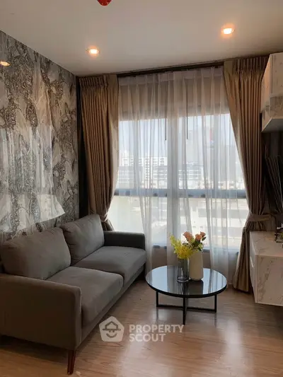 Modern living room with stylish decor and large window offering natural light.