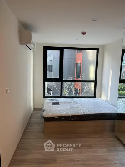 Modern bedroom with large windows and natural light in a contemporary apartment.