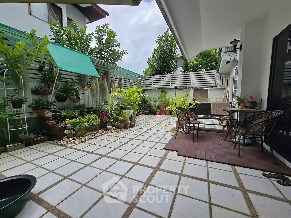 Charming garden patio with lush greenery and cozy seating area, perfect for outdoor relaxation.