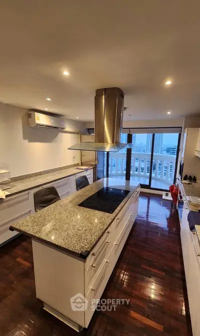 Spacious modern kitchen with island and open layout, featuring sleek appliances and polished wooden floors.