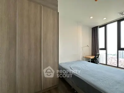 Modern bedroom with large windows and city view, featuring a sleek wardrobe and minimalist decor.