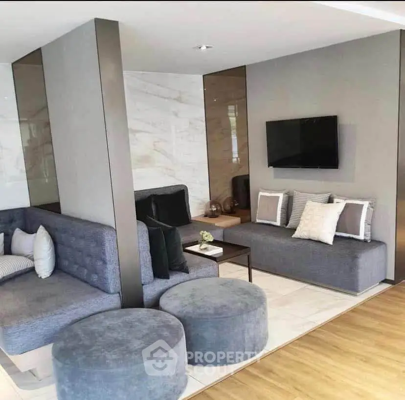 Modern living room with stylish gray sofas, wall-mounted TV, and elegant decor in a contemporary apartment.