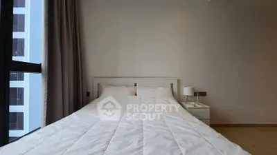 Modern bedroom with large window and minimalist decor in urban apartment.