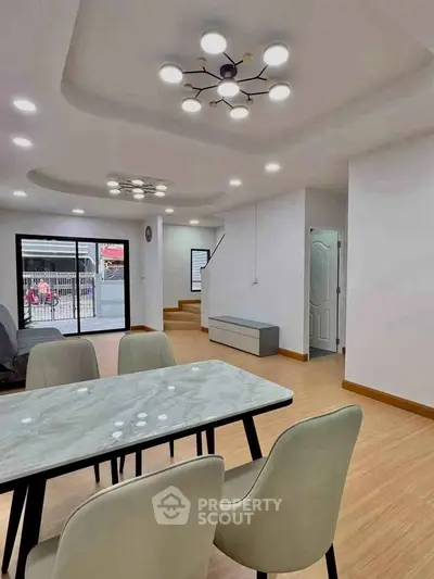 Modern open-plan living and dining area with stylish lighting and wooden flooring.