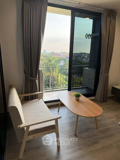 Charming living room with balcony view, cozy seating, and natural light in modern apartment.
