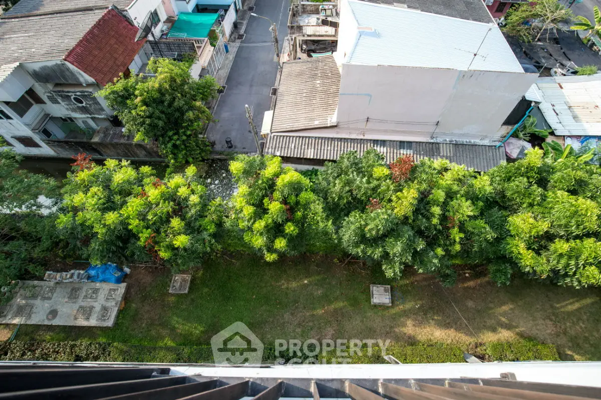 Aerial view of residential area with lush greenery and rooftops, showcasing urban living with nature.