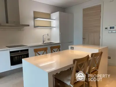 Sleek modern kitchen with integrated appliances, ample cabinetry, and a spacious island doubling as a casual dining area, perfect for entertaining.