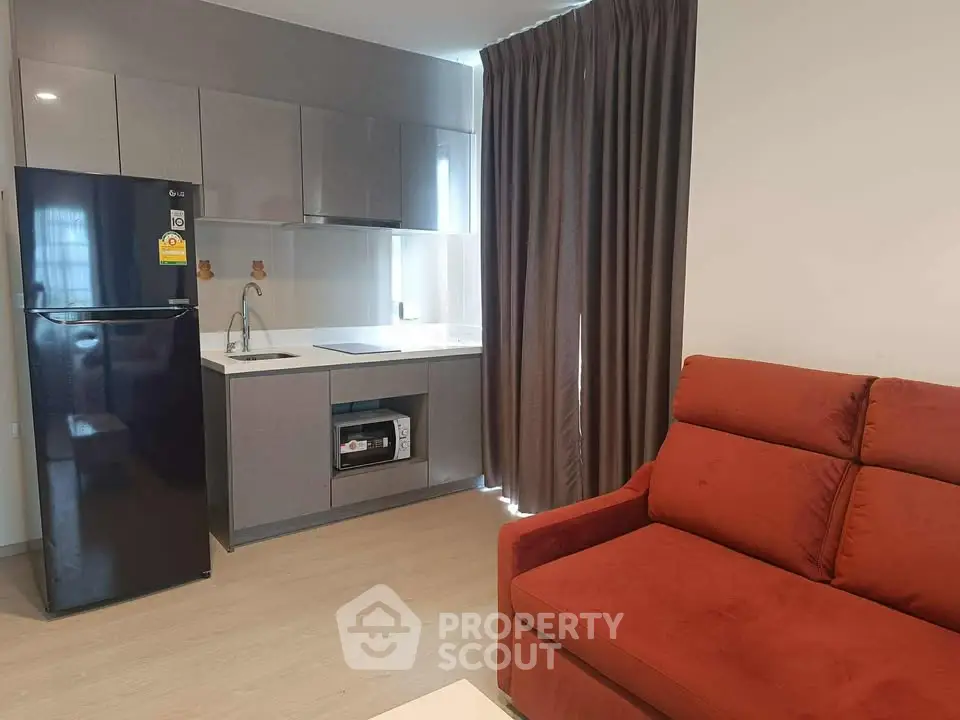 Modern apartment interior with sleek kitchen and cozy living area featuring a red sofa.