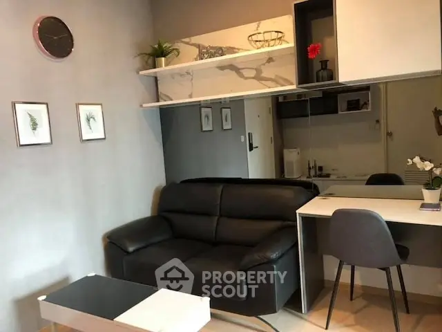 Modern living room with sleek black sofa, stylish decor, and functional workspace.