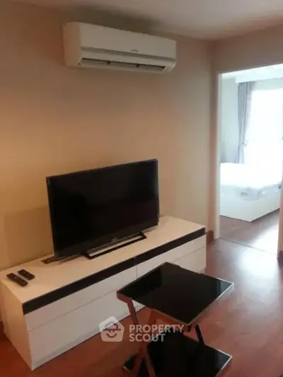 Modern living room with sleek TV setup and air conditioning, leading to a cozy bedroom.