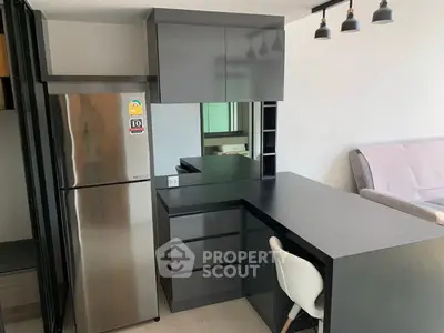 Modern kitchen with sleek black cabinetry and stainless steel fridge in stylish apartment.