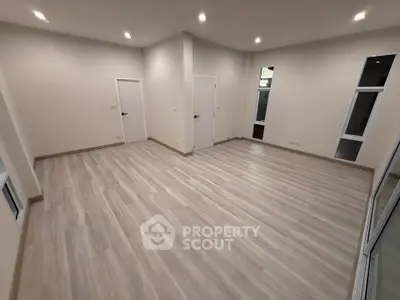 Spacious empty room with modern flooring and recessed lighting, perfect for customization.