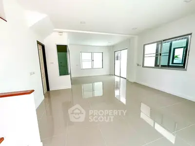 Spacious and bright living room with large windows and glossy tiled floors.