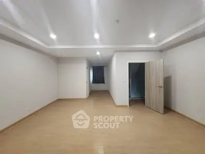 Spacious empty room with wooden flooring and recessed lighting, ideal for customization.