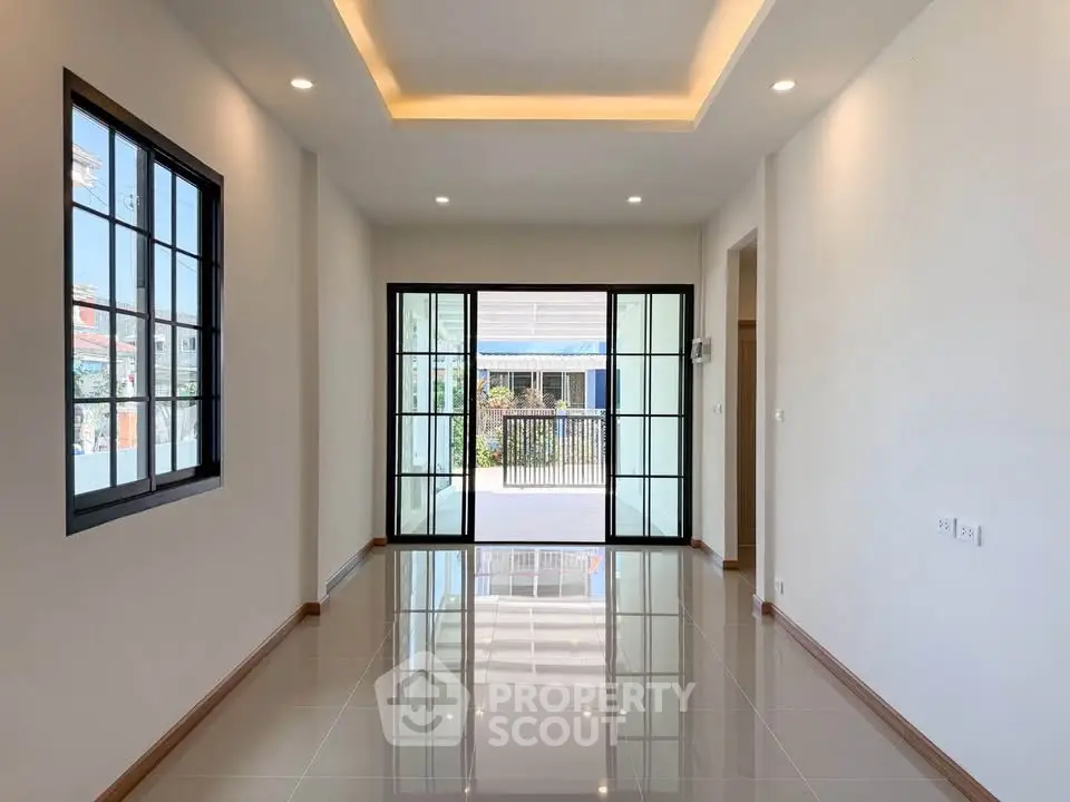 Spacious modern living room with large windows and glossy tiled floor, offering abundant natural light.