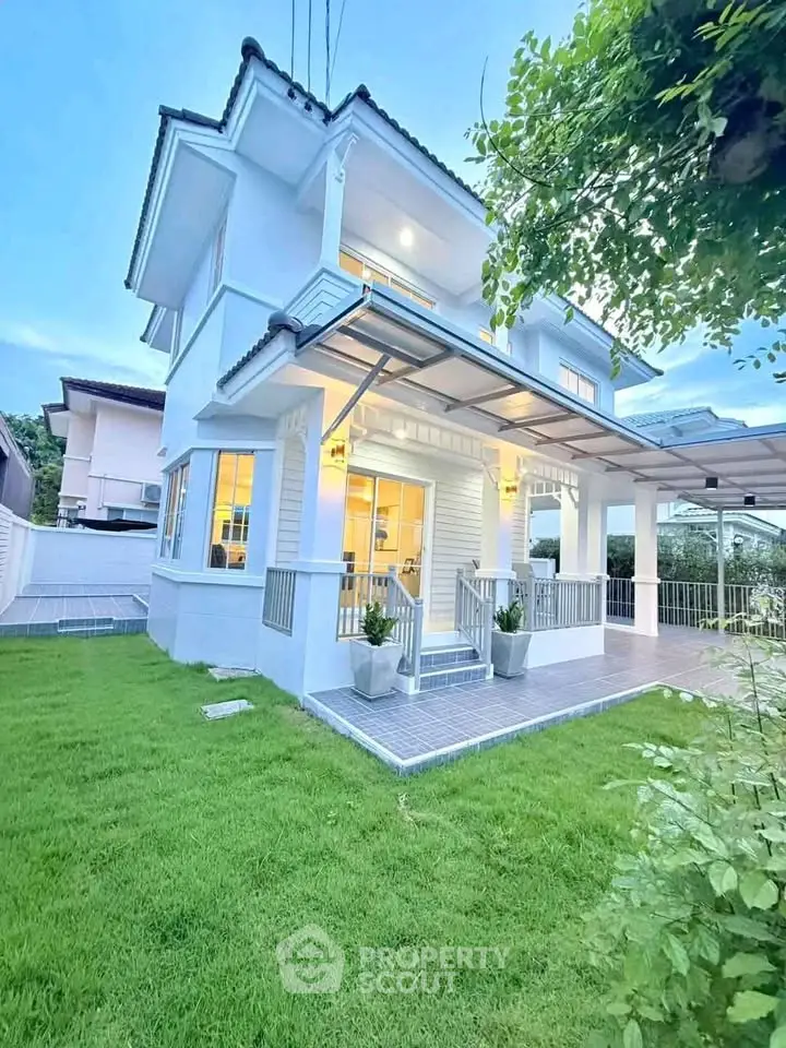 Charming two-story white house with lush green lawn and modern porch, perfect for family living.