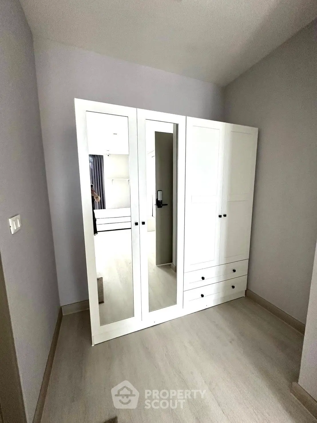 Spacious bedroom with modern white wardrobe and mirrored doors