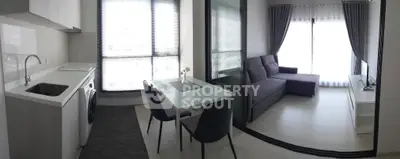 Modern apartment with open kitchen and cozy living area, featuring sleek furniture and ample natural light.
