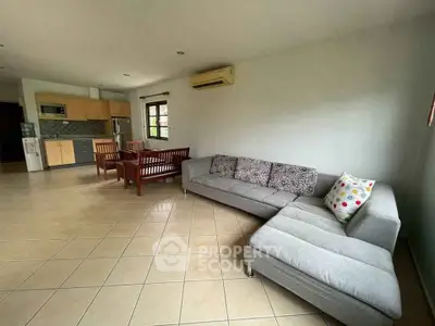Spacious living room with modern furniture and open kitchen layout in a bright, airy home.