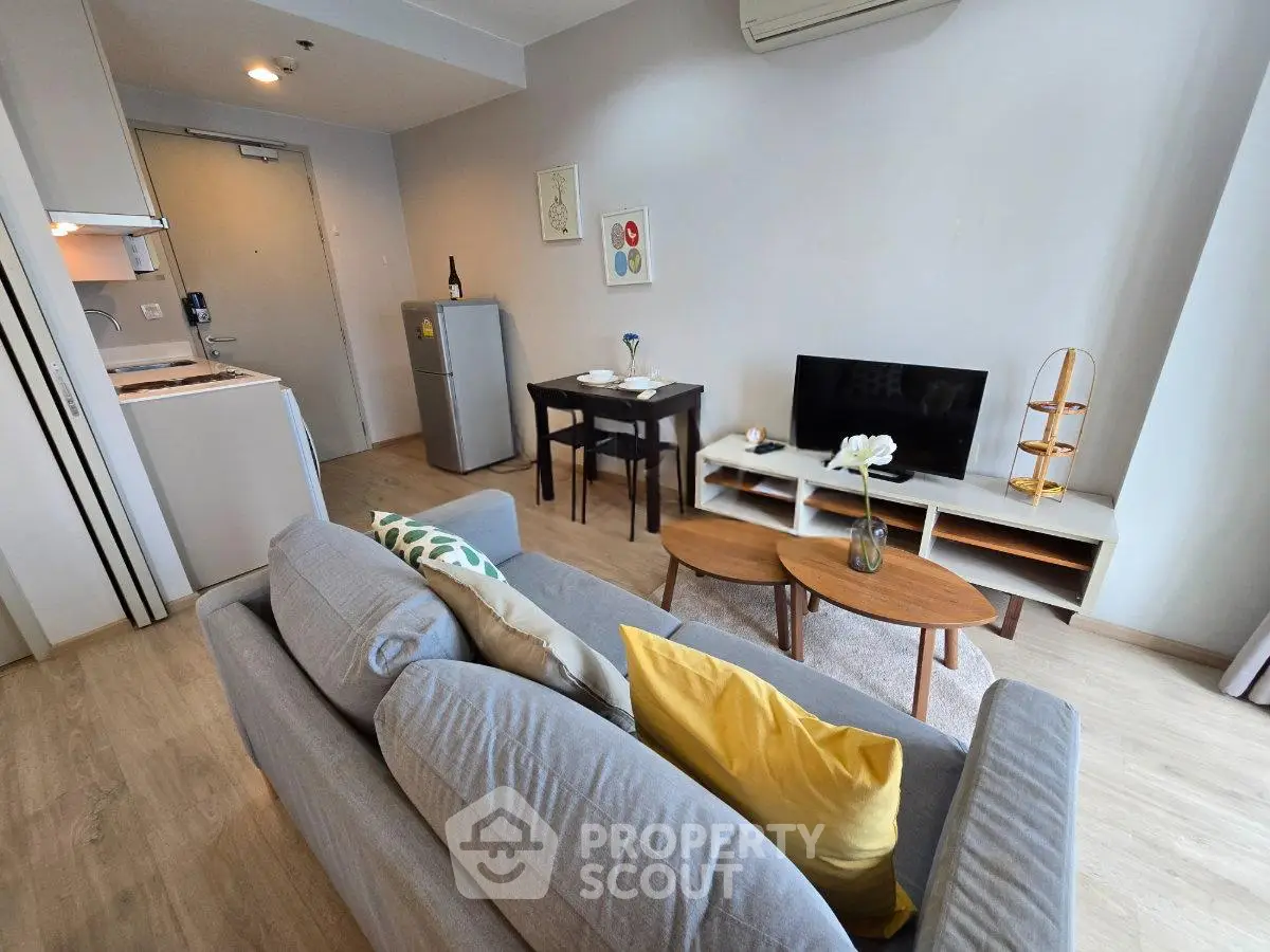 Modern living room with cozy sofa, dining area, and sleek kitchen in open layout apartment.