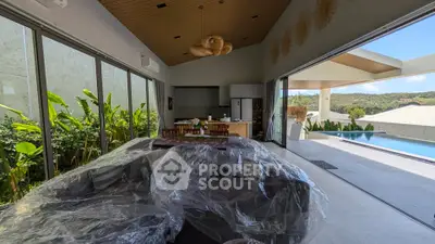 Luxurious open-plan living room with pool view and modern kitchen, perfect for entertaining.
