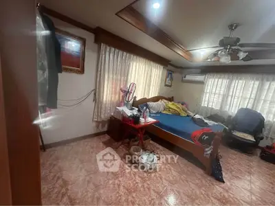 Spacious bedroom with wooden accents and natural light, featuring a ceiling fan and air conditioning.
