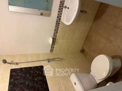Compact bathroom with shower, sink, and toilet in modern tile design.