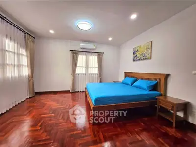 Spacious bedroom with wooden flooring and modern decor