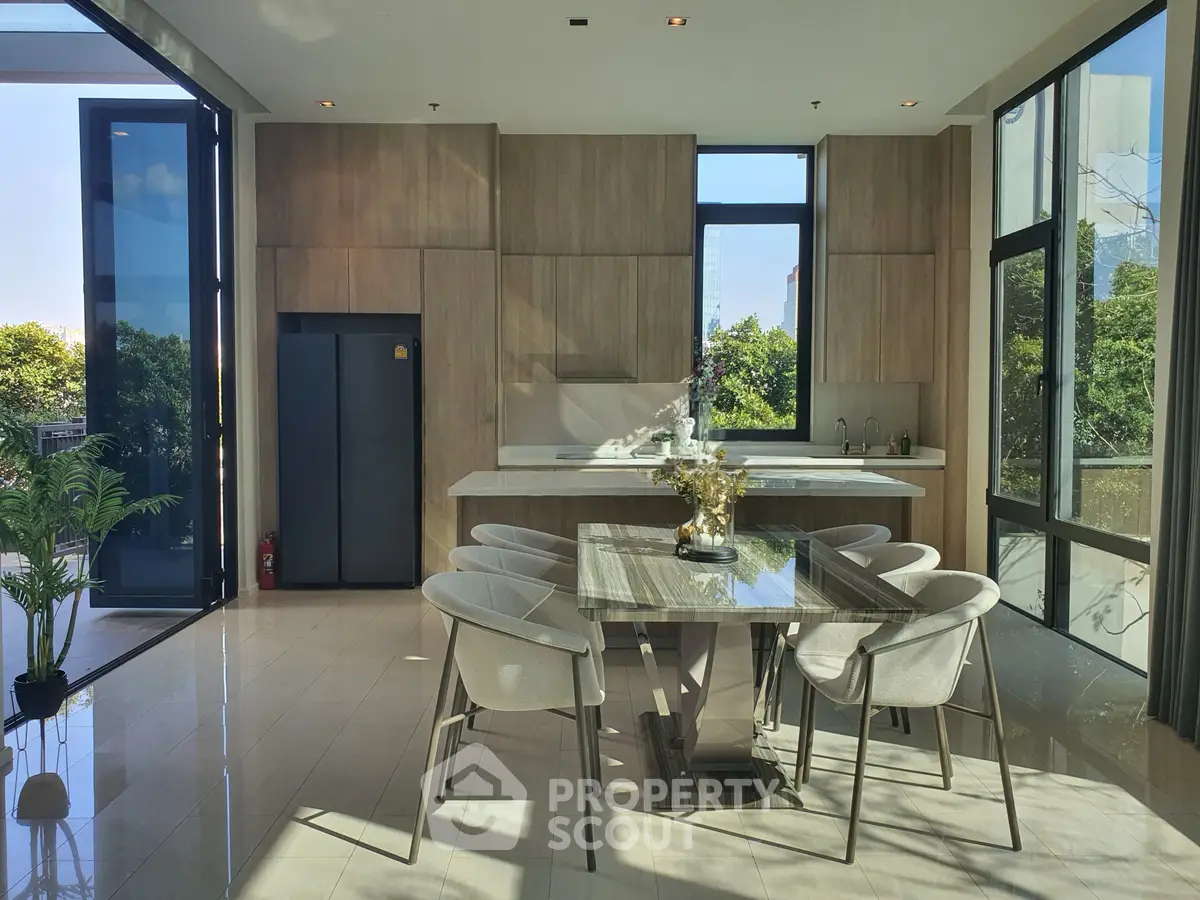 Luxurious modern kitchen with open layout and elegant dining area, featuring large windows and abundant natural light.
