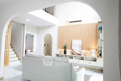 Modern living room with stylish decor and open layout, featuring a cozy white sofa and elegant wooden accents.