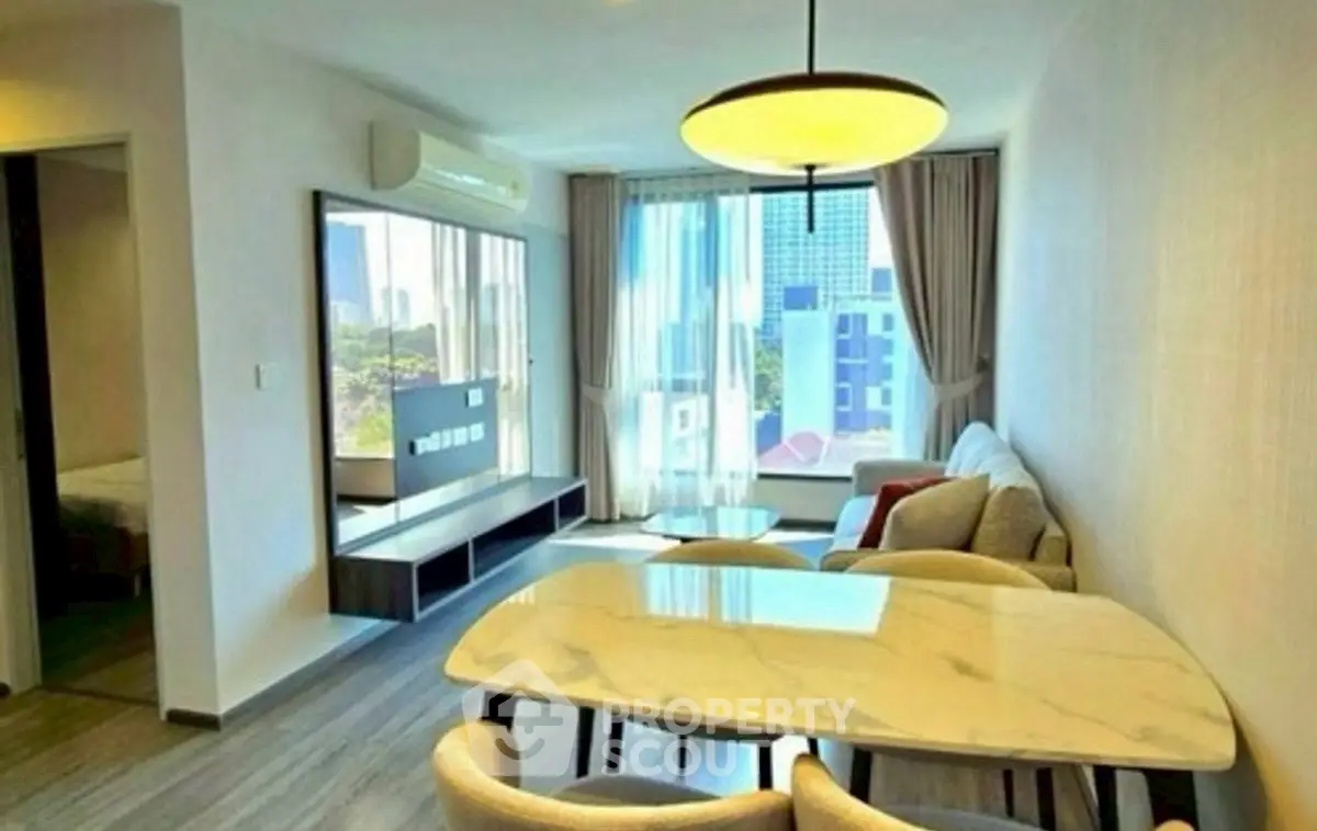 Modern living room with dining area and large window view in urban apartment.
