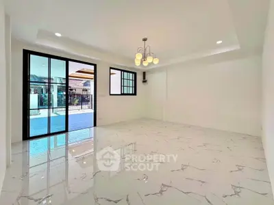 Spacious modern living room with marble flooring and large sliding glass doors leading to a patio.