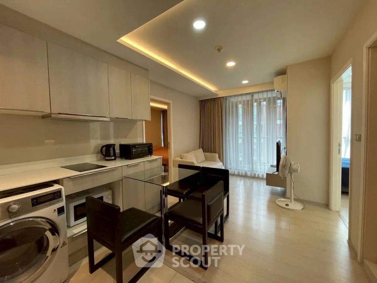 Modern open-plan living room with kitchen, featuring sleek furniture and natural light.