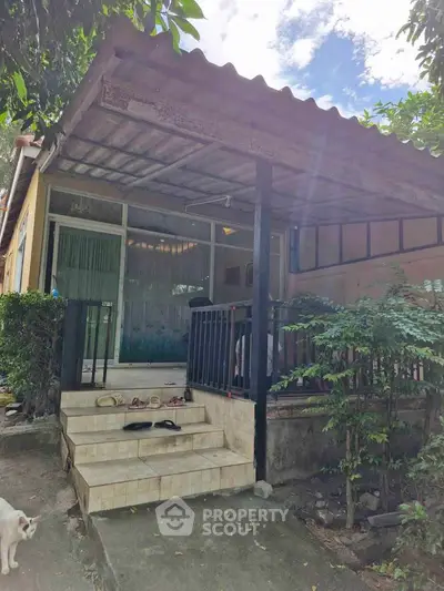 Charming small house with covered porch and lush greenery in a serene neighborhood.