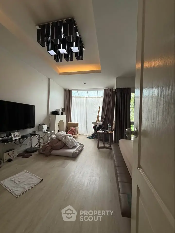 Spacious living room with modern lighting and large windows for natural light.