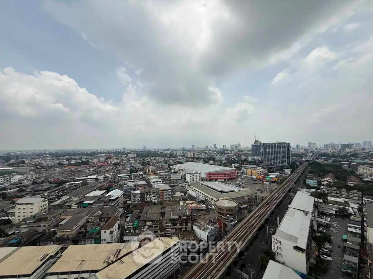 Stunning cityscape view from high-rise building showcasing urban skyline and railway tracks.