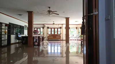 Spacious living room with glossy floors, ceiling fans, and large windows offering natural light.