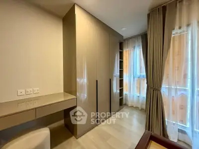 Modern bedroom with sleek wardrobe and natural light through large windows.