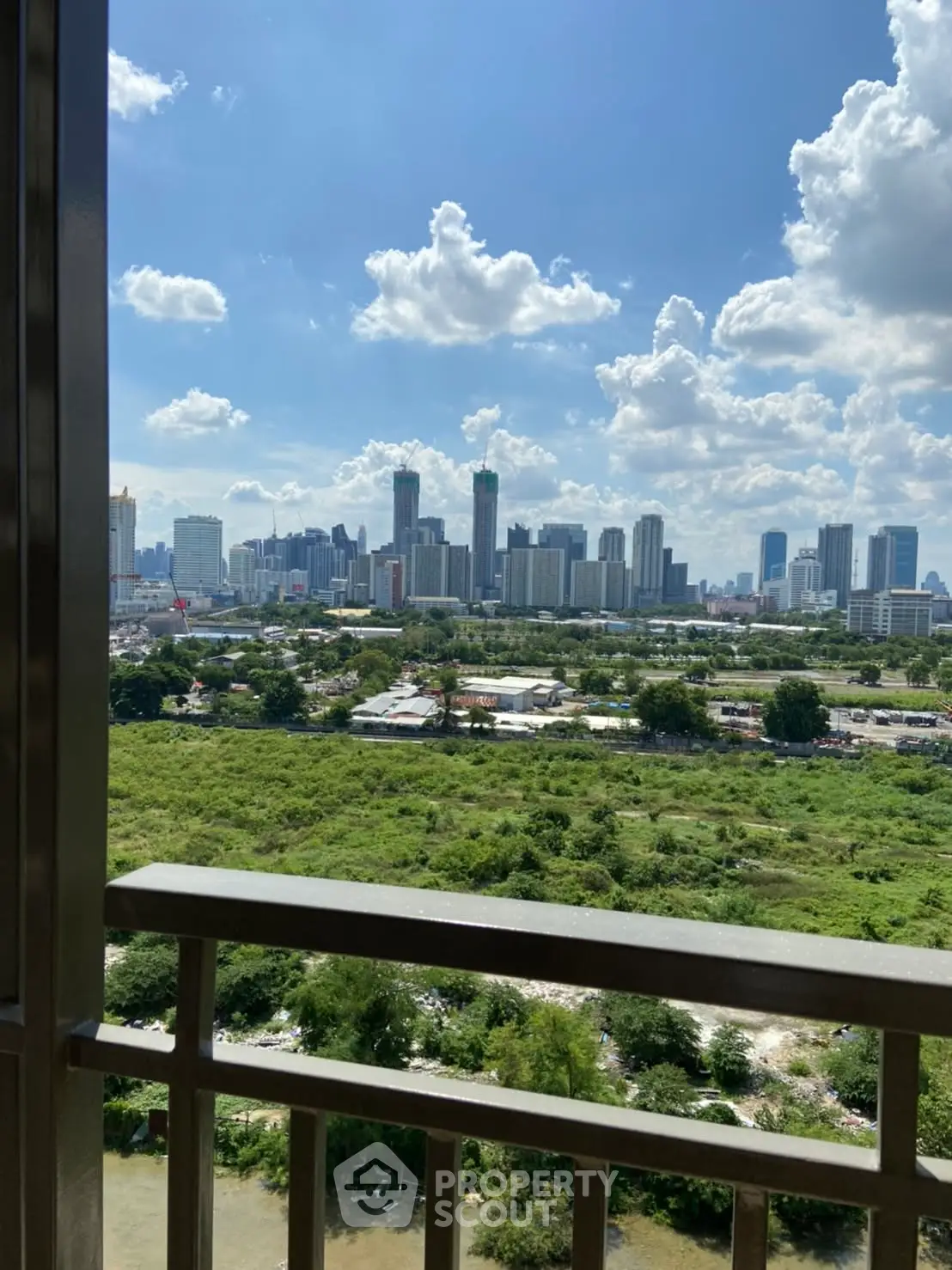 Stunning cityscape view from a high-rise balcony overlooking lush greenery and urban skyline.